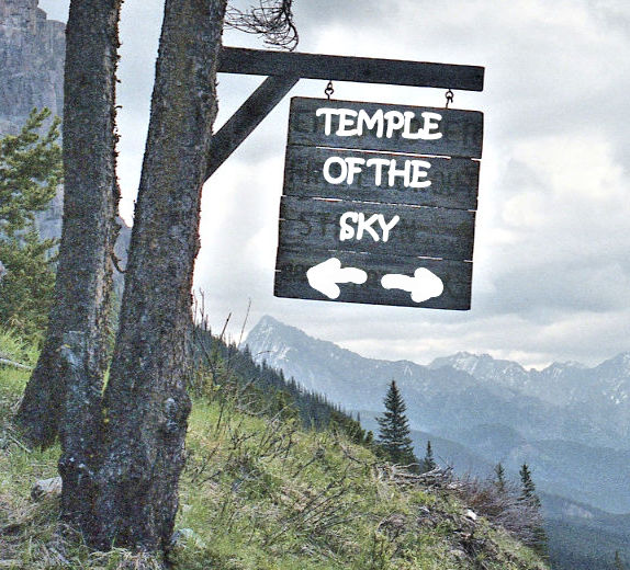 A wooden sign overhanging a panorama of mountains